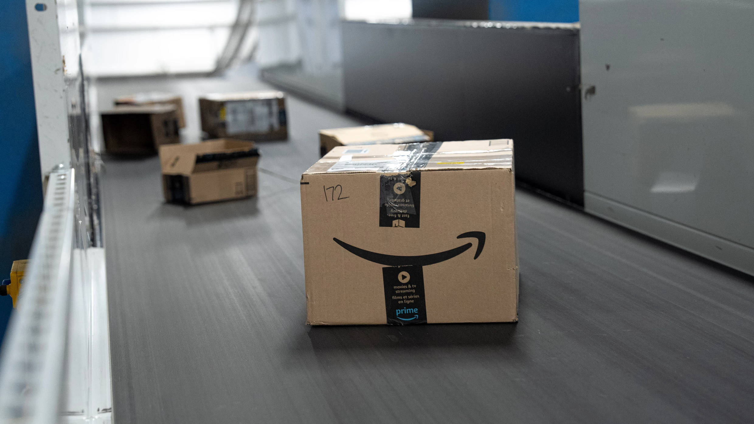 Colis Amazon Prime sur tapis roulant dans un entrepôt - logistique Amazon FBA